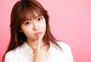 ピンク色の背景にポーズをとった、長くまっすぐな茶色の髪と白い肌を持つ若いアジア人女性...。