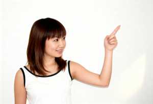 肩までの長さのストレートなボブヘアを持ち、人差し指を上に向けてわずかな笑みを浮かべた...。