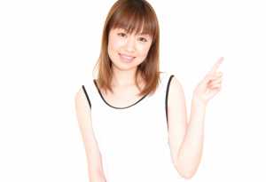 人差し指で上を指し、明るい表情をしたアジア系の若い女性。