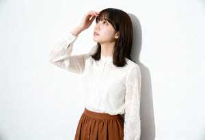 無地の白い壁に立っている若い女性。