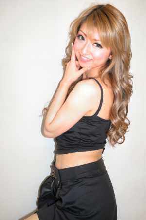 黒いクロップトップと黒いタイトなスカートを着て、わずかな笑顔で自信を持ってポーズをと...。