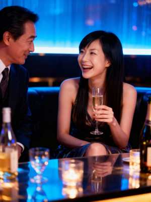 薄暗いバーのカウンターでシャンパンを楽しむカップルのロマンチックなシーン。