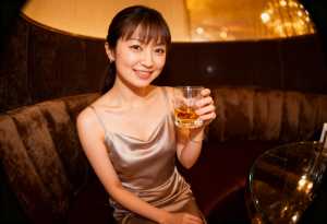 薄暗いレストランのソファに座り、右手にウィスキーのグラスを持った若い女性の写実的なポ...。