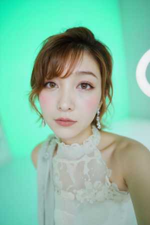 柔らかな光を当てた緑の背景に、薄手の白いドレスと揺れるイヤリングを身に着けた、柔らか...。