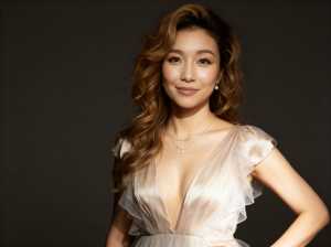 深くウェーブのかかった茶色の髪をした若い女性が、大きく開いたネックラインとフリルの袖...。