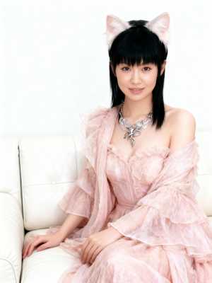 猫耳を生やした若い女性が白いソファにリラックスしたポーズで座り、フリルの重ね着とステ...。