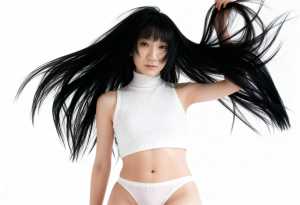 白いリブ編みのクロップトップとそれと一致するパンティーを着て、長い黒髪でポーズをとる...。