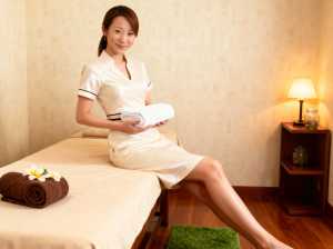 スパのような環境でマッサージ テーブルに座っている若いアジア人女性の写実的な高品質画像。