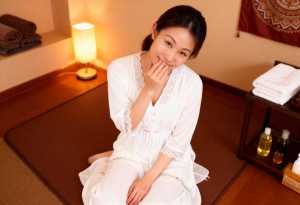 白いローブを着てスパのマットに座っている女性を正面カメラのアングルから写実的に撮影したもの。