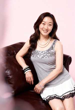 柔らかいピンクの背景に茶色の革張りのソファに座っている女性をポートレートアングルから...。