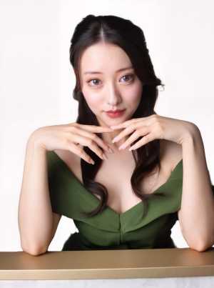 中くらいの大きさの胸を強調する緑のオフショルダーのドレスを着た、ウェーブのかかった長...。