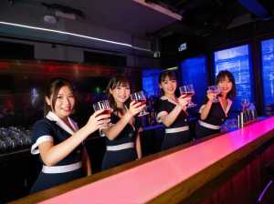 バーカウンターの後ろに立ち、白のアクセントが付いたネイビーブルーの制服を着て赤ワイン...。