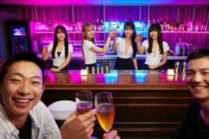 ネオン輝くバーのバーカウンターでドリンクを楽しむ 5 人のアジア人の若者のグループを...。