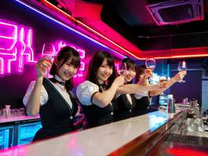 ネオン輝くバーのバーカウンターの後ろに立っている5人のアジア人女性のグループを正面か...。