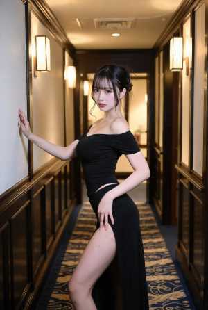 スリットの入った露出度の高い黒いドレスを着て、長い廊下で自信を持ってポーズをとる若い...。
