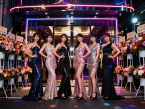 夜にカラフルなネオンが輝く建物の前に立ち、集合写真を撮る 7 人の若い女性のグループ。