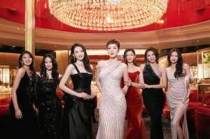 豪華なロビーに立ち、大きなシャンデリアの前で写真を撮る 7 人の女性のグループ。