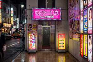 ネオンが輝く夜の日本料理店の入り口をローアングルから撮影した写真。