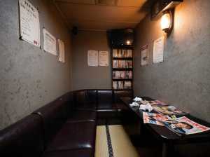 薄暗く、居心地の良い雰囲気のお部屋で、コーナーブースと新聞を敷いたテーブルが特徴です。