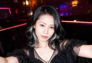 ネオンライトを背景に薄暗いナイトクラブで自撮りをする若い女性のポートレート。