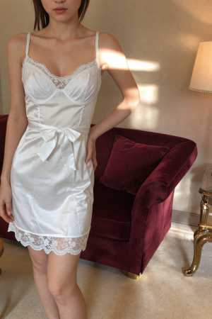 ワインレッドのベルベットのソファとランプのある居心地の良いリビング ルームに立つ、白...。