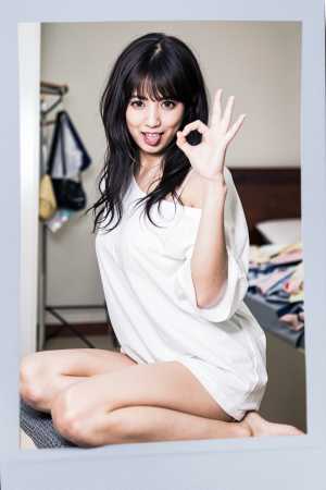 楽屋のベッドに座り、右手で「OK」のジェスチャーをしている若い女性のポラロイド写真。