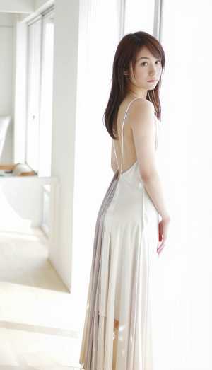 白いロングドレスを着てモダンなインテリア空間に立つ若い女性を横から見た写真のようにリ...。