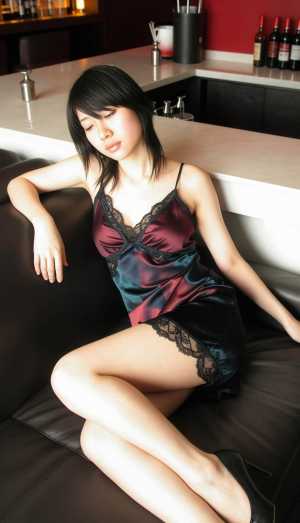 薄暗いバーの中でソファに座り、レースのトリムが付いたシルクのようなスリップ ドレスを...。