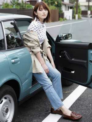 黒い花柄の白いブラウス、ブルー ジーンズ、茶色のローファーからなるカジュアルな服装を...。