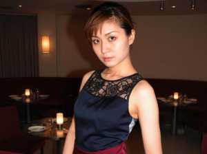 薄暗いレストランに立つ若い女性の写実的なポートレート。