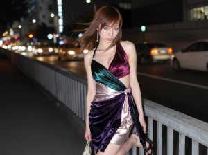 見事な紫と緑のベルベットのドレスを着て、夜の橋の上で自信を持ってポーズをとる若い女性...。