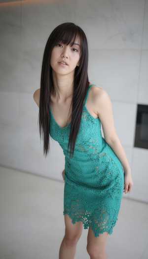 屋内で自信を持ってポーズをとるターコイズブルーのかぎ針編みのドレスを着た若い女性をポ...。