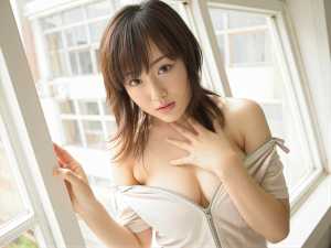 胸の谷間を露出させるためにたくし上げられた明るい色のオフショルダーのトップスを着て、...。