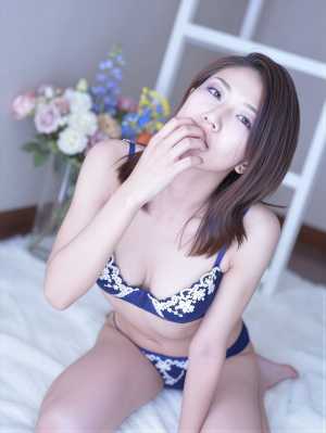 青いレースのブラとおそろいのパンティーを着てベッドに座り、思慮深い表情でポーズをとっ...。