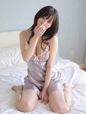 花の刺繍が施された絹のようなナイトガウンを着て、明るい色の寝室のベッドに座っている若...。