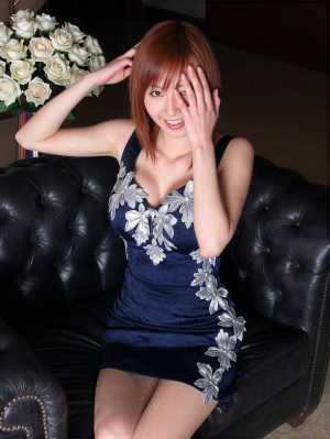 白いバラの花束を背景に、黒い革張りのソファに座っている若い女性を正面から写実的に撮影...。