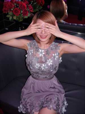 薄暗い部屋で黒い革張りのソファに座り、目を手で覆っている若い女性を正面カメラのアング...。