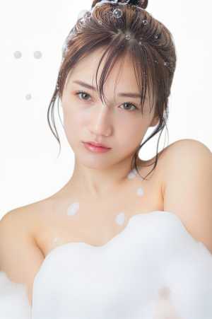 白い泡で満たされた浴槽に座っている、白い肌と茶色の髪を乱雑なお団子で束ねた若い女性の...。