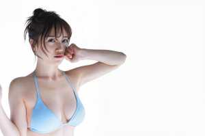 無地の白を背景に、水色のビキニを着て自信を持ってポーズをとる若い女性をポートレートア...。