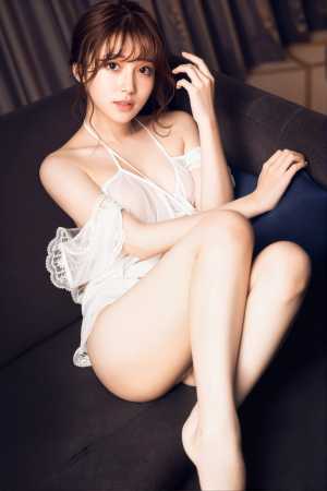 薄手の白いドレスを着て、リラックスしたポーズでソファに座っている若い女性を横から撮っ...。