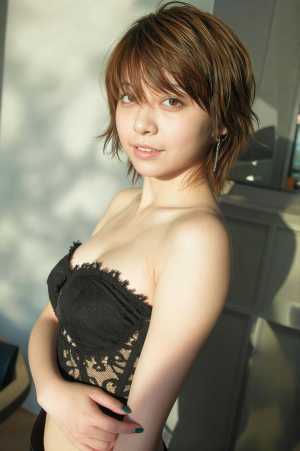 黒いレースのストラップレス トップとぶら下がっているイヤリングを着た、短い茶色の髪と...。