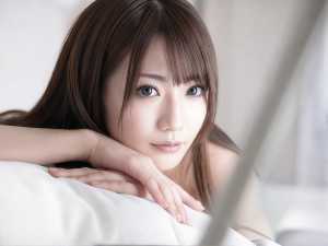 長く真っ直ぐな茶色の髪と印象的な青い目を持ち、カメラを直接見つめながら顎を手に乗せた...。