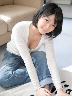 白い長袖シャツとブルー ジーンズを着て、モダンなリビング ルームの敷物の上にしゃがむ...。