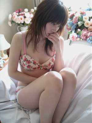 居心地の良いリビング ルームの白いソファに座り、ピンクの花柄のブラとお揃いのパンティ...。