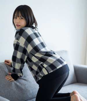 黒のセーター姿でソファに佇む女性