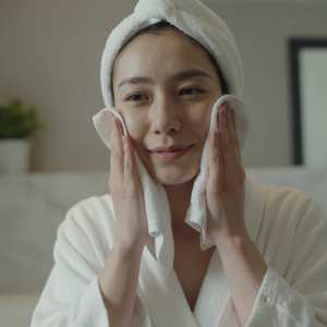 洗面所で洗顔後に顔を拭く女性