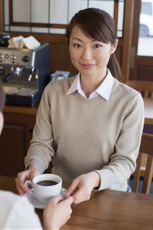 喫茶店でコーヒーを提供する女性