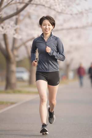 桜並木をジョギングする女性