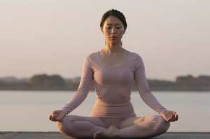 夕暮れの湖畔で瞑想する女性