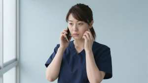 廊下で電話をする看護師